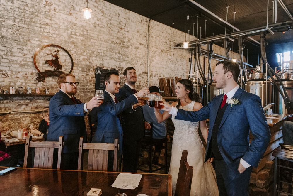 Bride and groom cheer with their groomsmen at brewery in north carolina