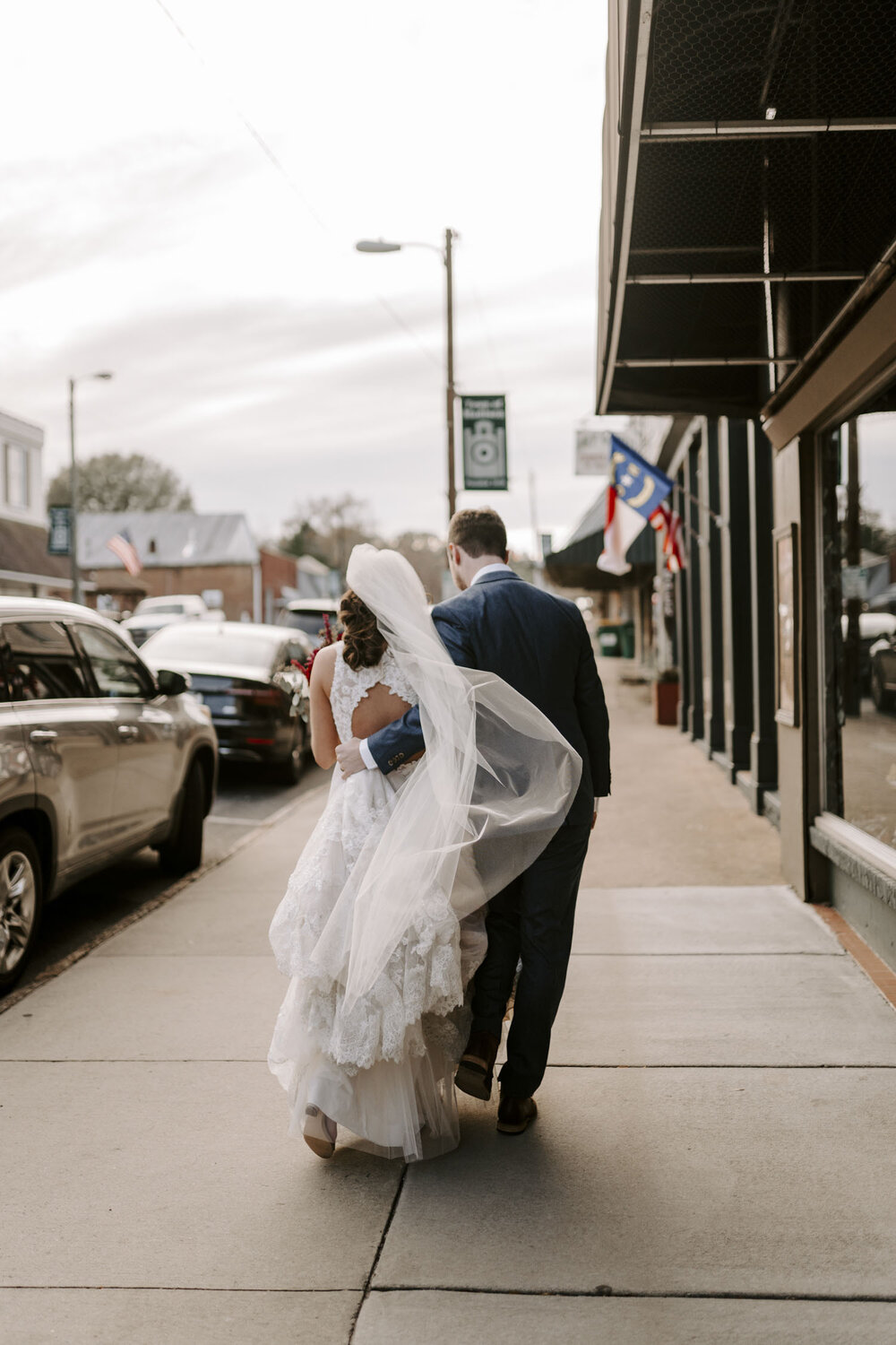 bride and groom walking downtown at their windy fall wedding in Winston-Salem, NC