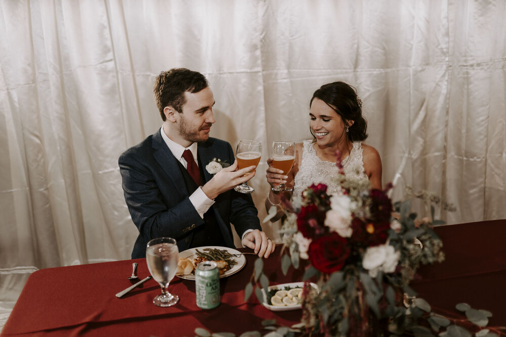 Craft Beer loving couple toast at their fall wedding reception