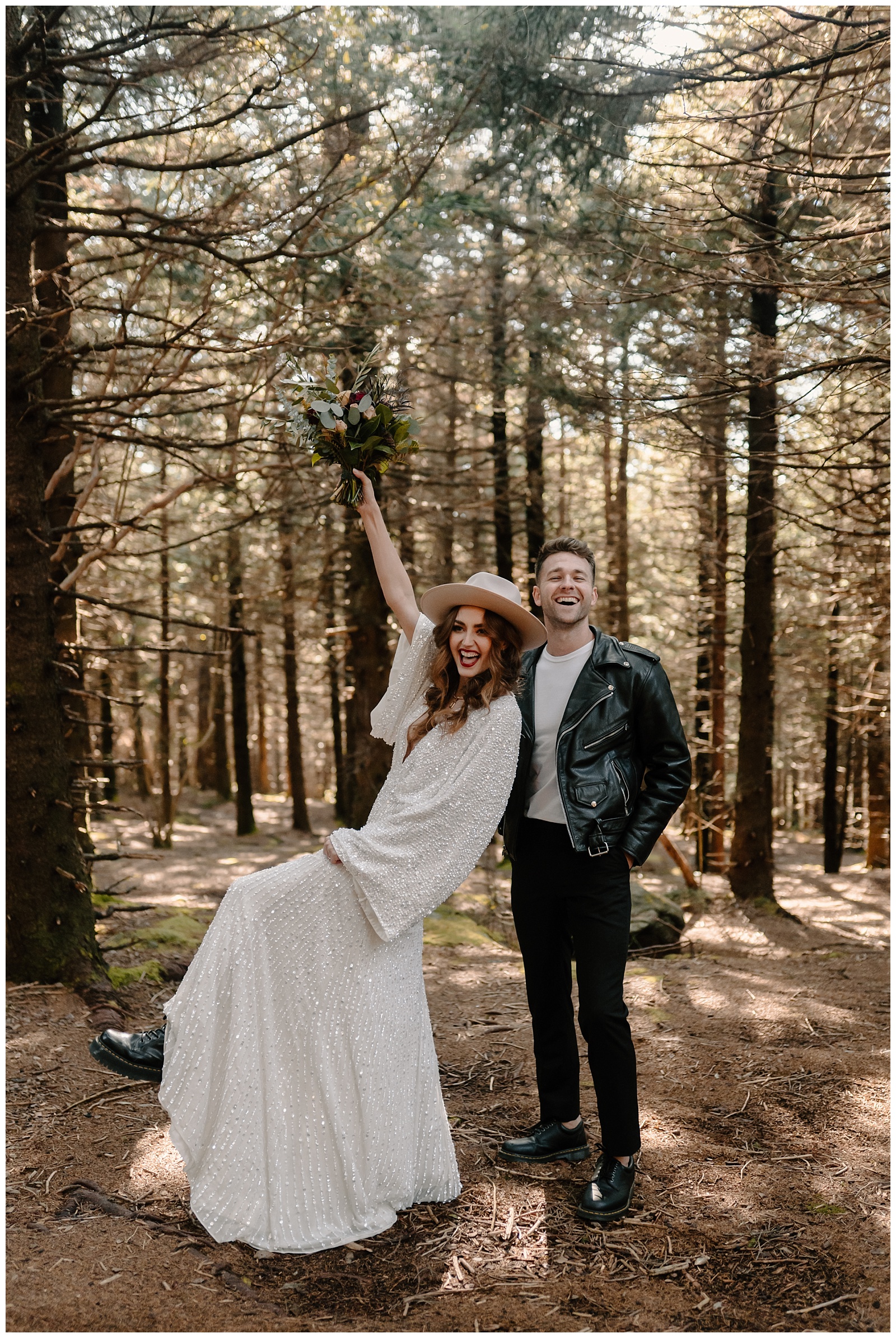 bride and groom celebrate eloping in the woods throwing flowers in the air