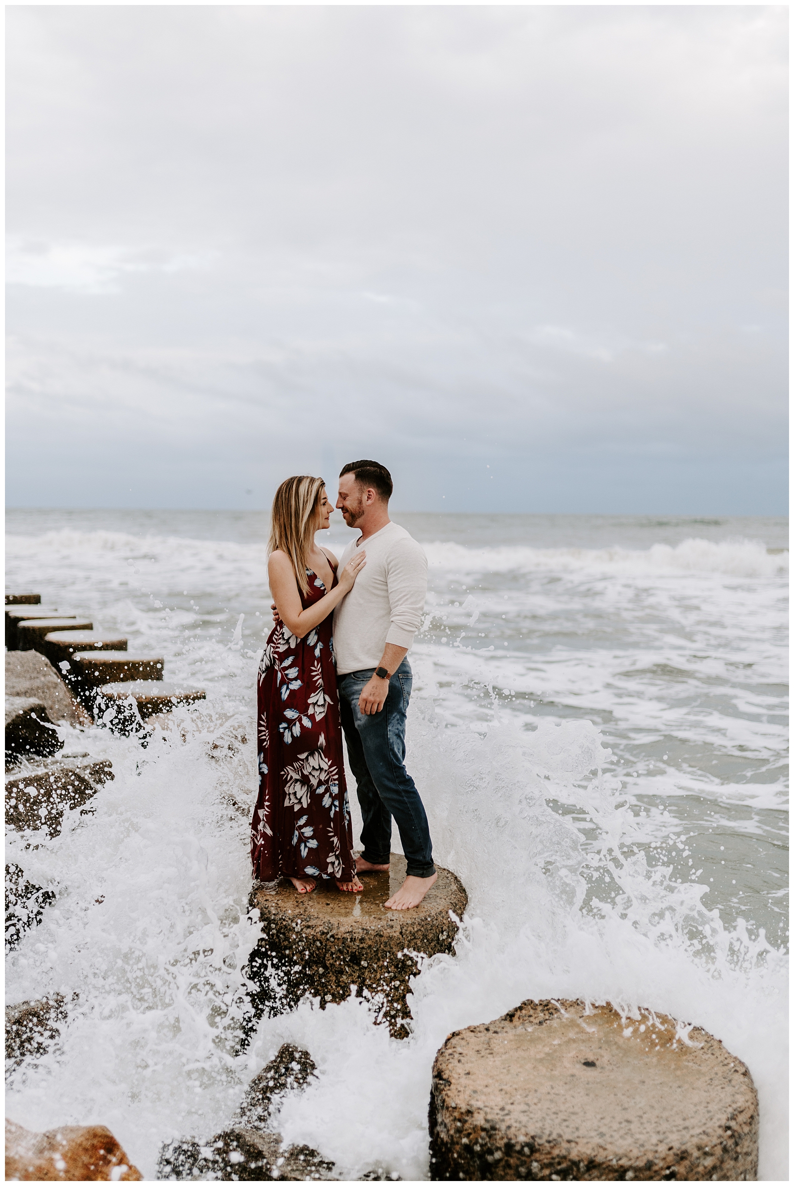 Couple in front of crashing waves at their adventurous beach engagement session in Wilmington, NC