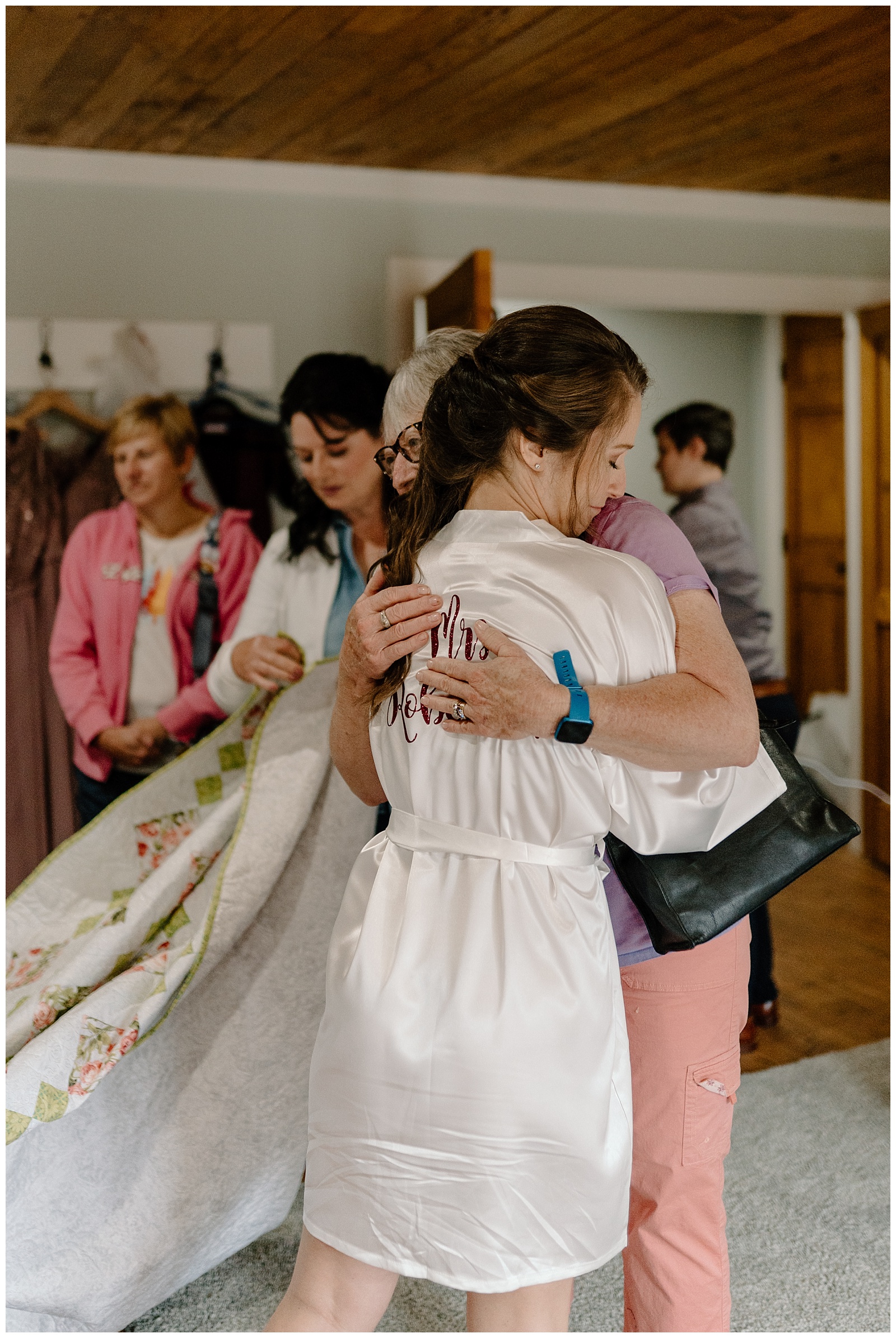 A bride opens a gift bag on her wedding day, which includes a quilt hand made by a family member.