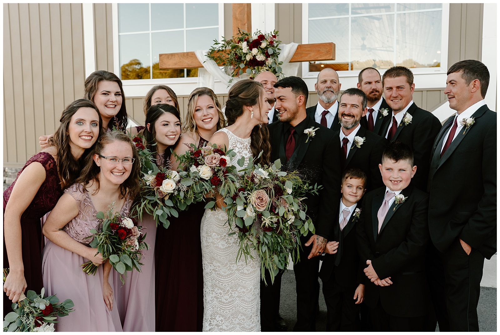 Close up image of whole wedding party laughing and smiling while bride and groom look at each other