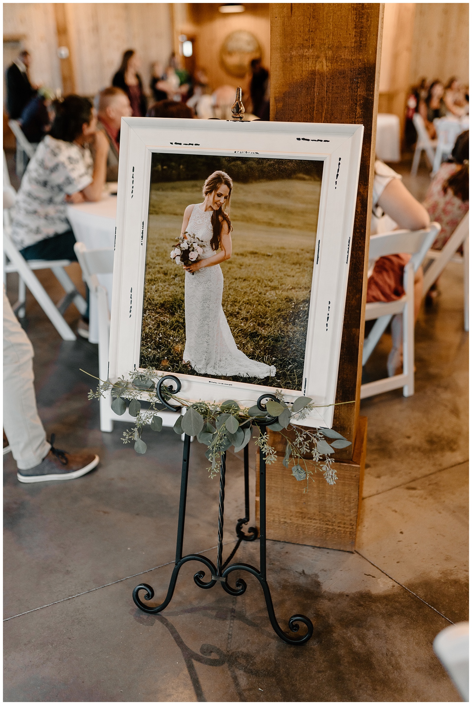 Portrait of a bride in a large white frame on display at her wedding reception