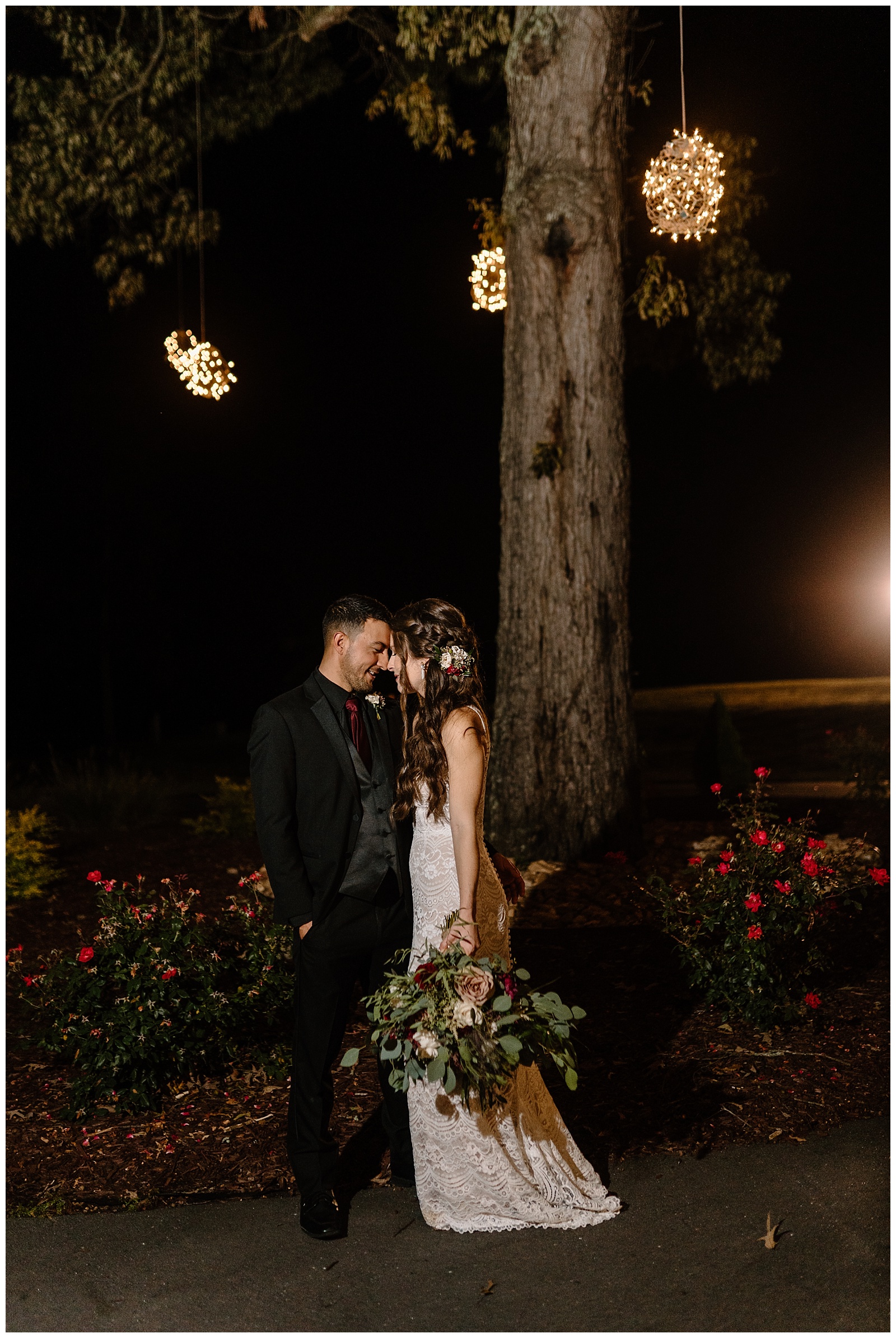 Night time portrait of groom in black suit and bride in lace dress looking at each other