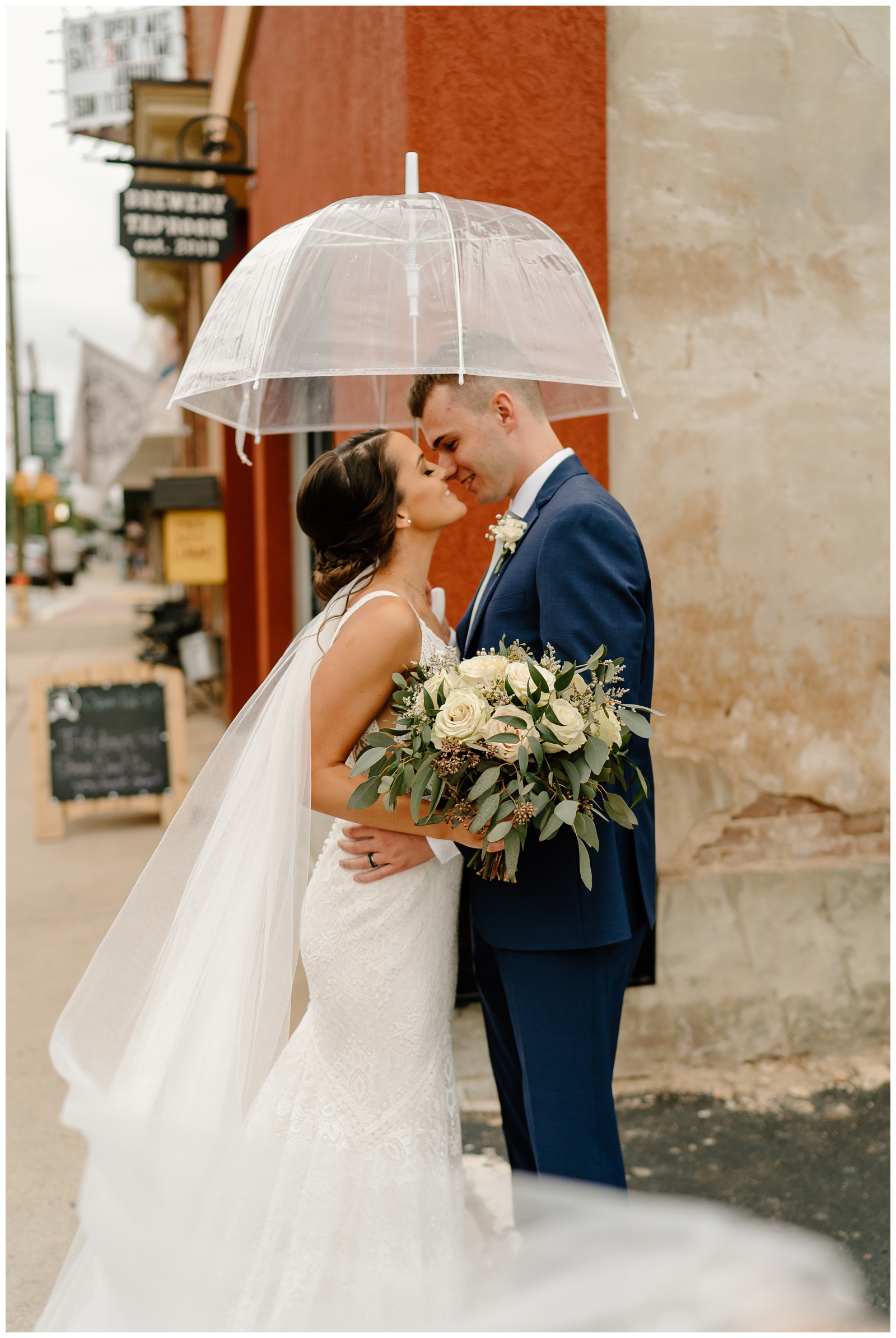 Rainy wedding day portraits with clear umbrella, fluffly bouquet, mermaid lace dress and long veil, modern indie wedding