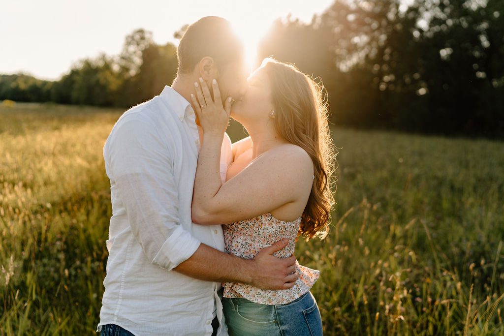 Couple kissing in open field in North Carolina with golden hour light 
