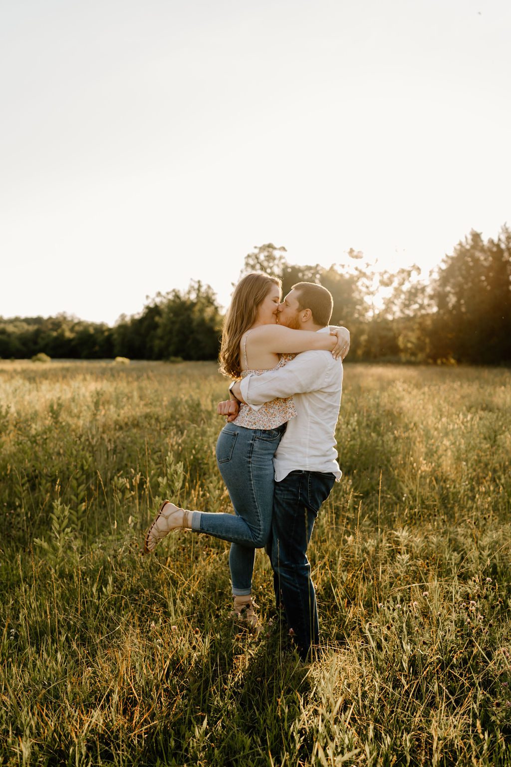 Couple hugging in open field in North Carolina with golden hour light 
