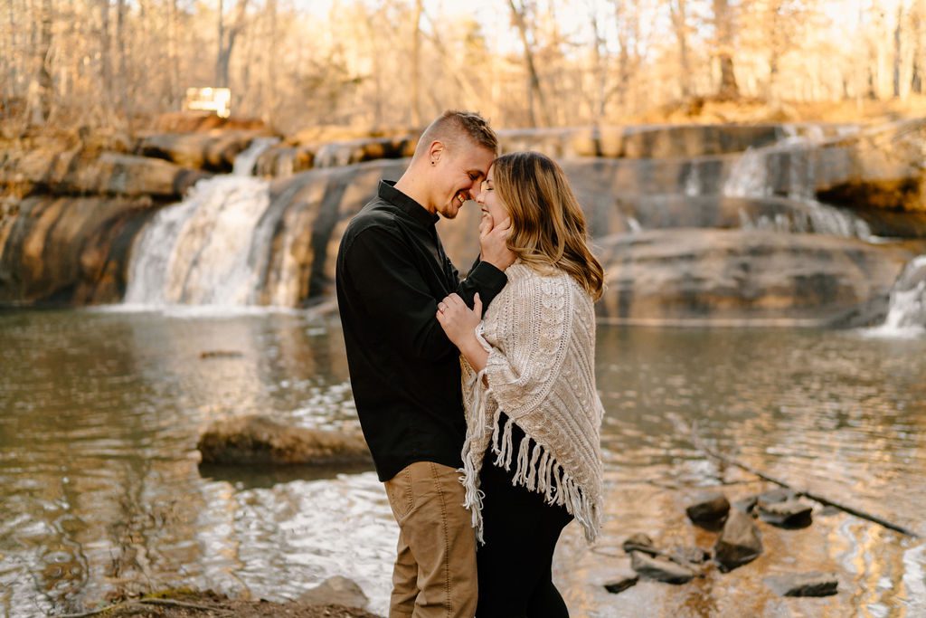 Couple posing in front of a waterfall for playful sunset engagement session in North Carolina