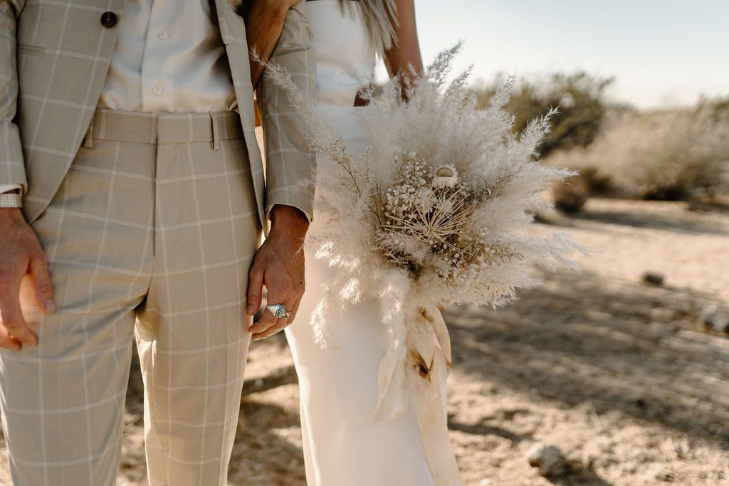 bride and groom posing with boho elopement flowers