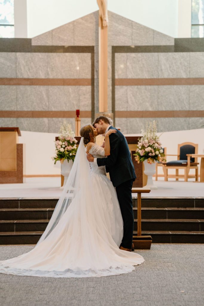 Bride and groom kissing at the altar